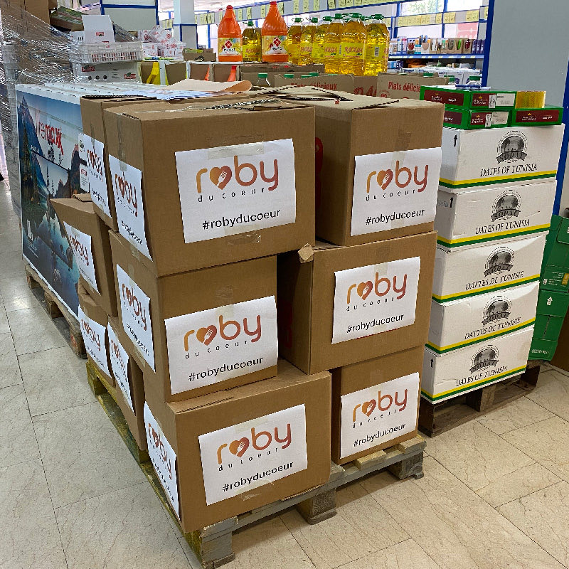 A pallet of Roby du Coeur boxes stacked in a store aisle, next to crates of dates.