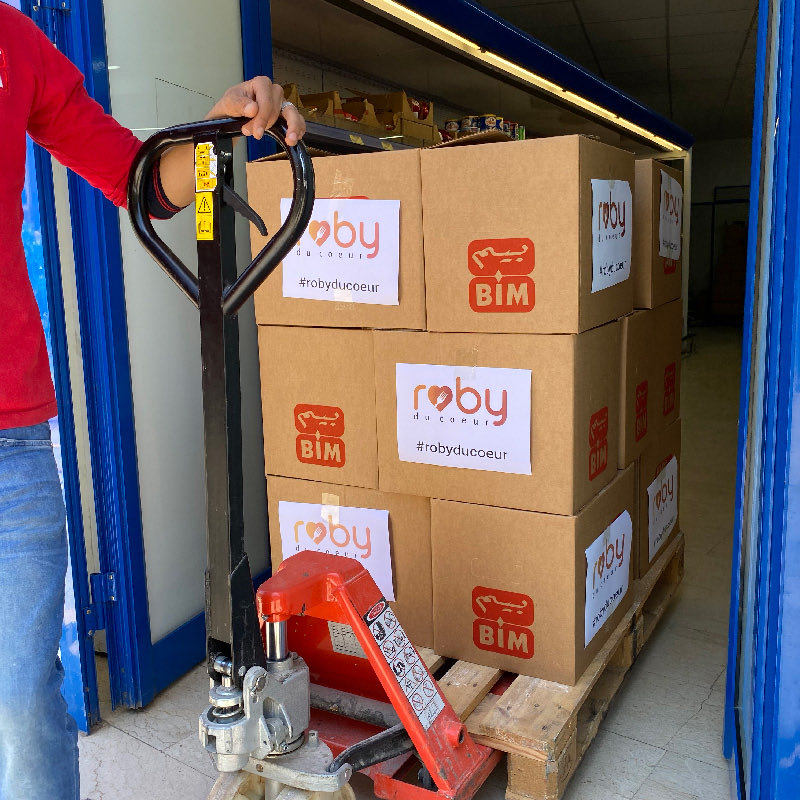A pallet jack loaded with boxes of donations manoeuvres towards a truck.
